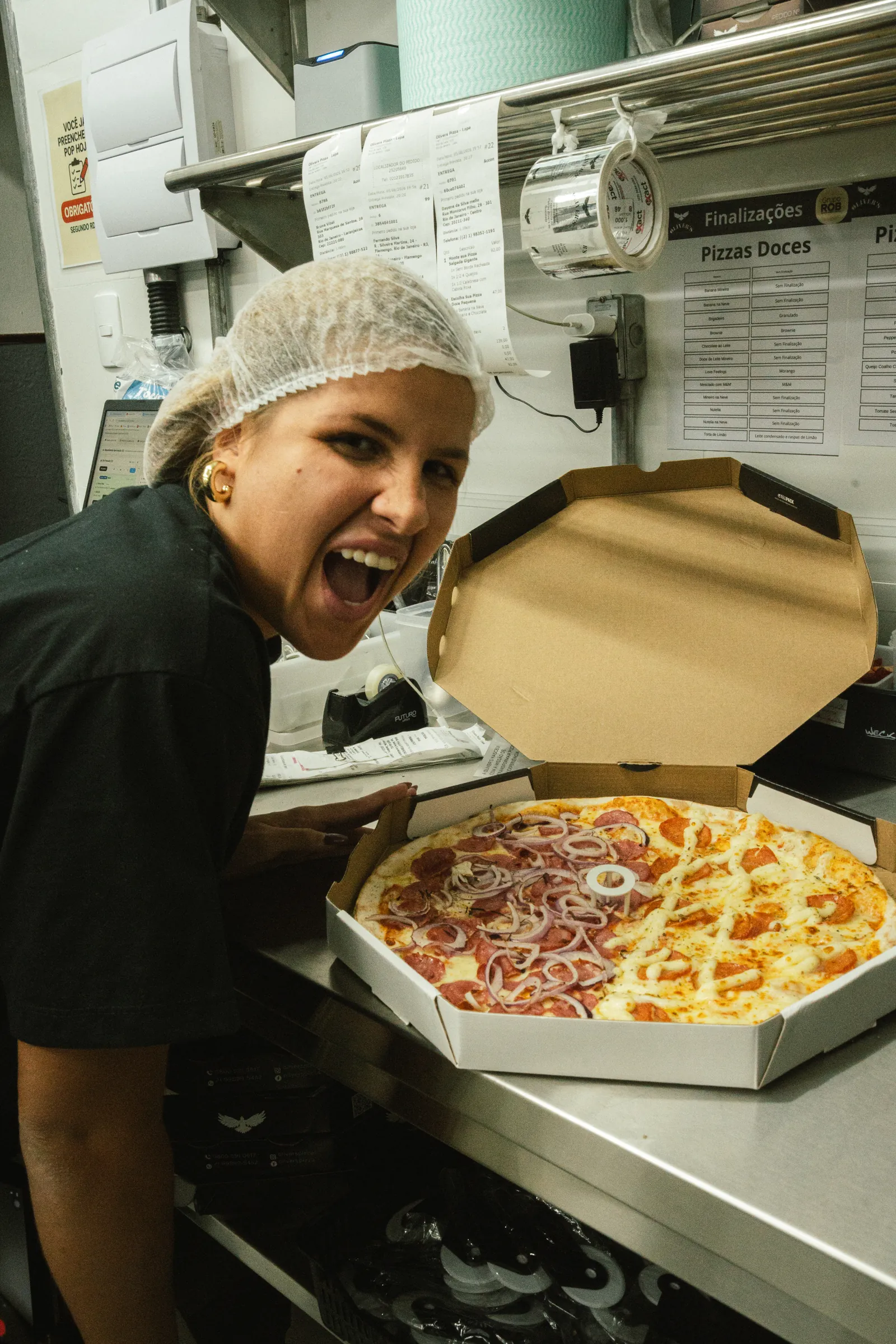 Colaboradora da unidade com uma pizza pronta para entrega