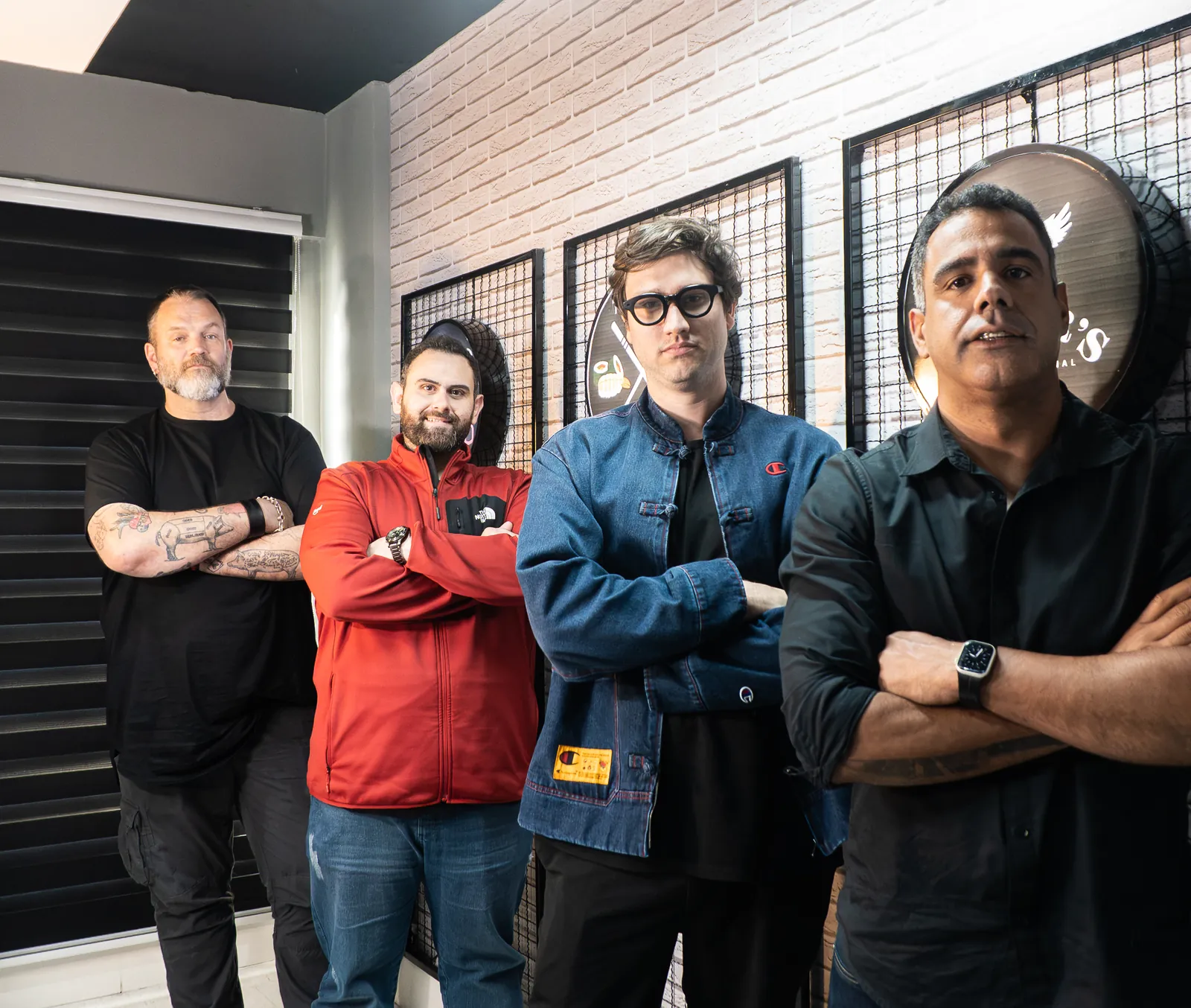Sócios do grupo diante da parede com os discos das marcas